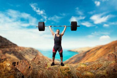 Strong weightlifter takes a weight on the top of mountain, deadlift, sea or ocean on background. Weightlifting workout outdoor, bodybuilding training clipart