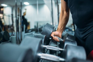 Erkek atlet ağır dumbbell el, spor salonu zemin üzerine iç alır. Halter egzersiz spor ve fitness kulübü, ağırlık kavramı seçme