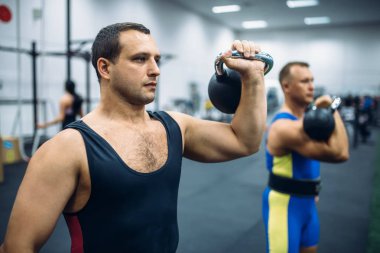 Güçlü erkek sporcular gym, ağırlıkları ile kettlebell kaldırma. Spor ve fitness kulübü halter egzersiz