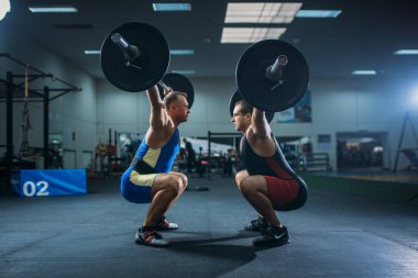 İki erkek halterci Barbell, spor salonu iç arka plan üzerinde ile ağız kavgası yapıyor. Halter egzersiz spor ya da fitness club, vücut geliştirme
