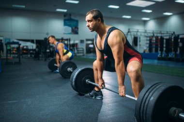 Egzersiz spor salonu iç arka plan üzerinde Barbell ile iki güçlü halterci. Halter egzersiz spor ya da fitness club, vücut geliştirme