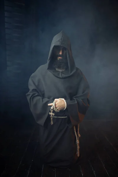 中世の修道士は 手と祈り 宗教の木製の十字架を保持しています 暗いマントの神秘的な修道士 神秘と精神 — ストック写真