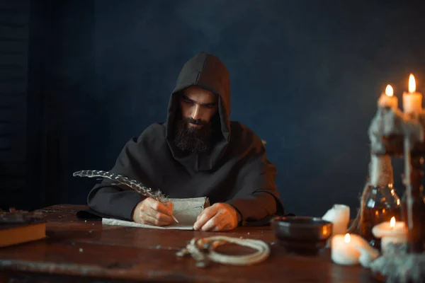 中世纪的和尚坐在桌旁 用鹅毛 顶视图 秘密经文写字 神秘的修士在黑暗的斗篷 神秘与灵性 — 图库照片