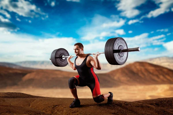 肌肉举重运动员在背景下 用杠铃 死气肿 沙质的沙漠山谷做蹲 举重户外锻炼 健美训练 — 图库照片