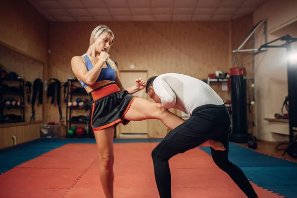 Female person makes a kick in the groin, self defense workout with male personal trainer, gym interior on background. Woman on training, self-defense practice — Stock Image Female Person Makes Kick Groin Self Defense Workout Male Personal Stock Picture