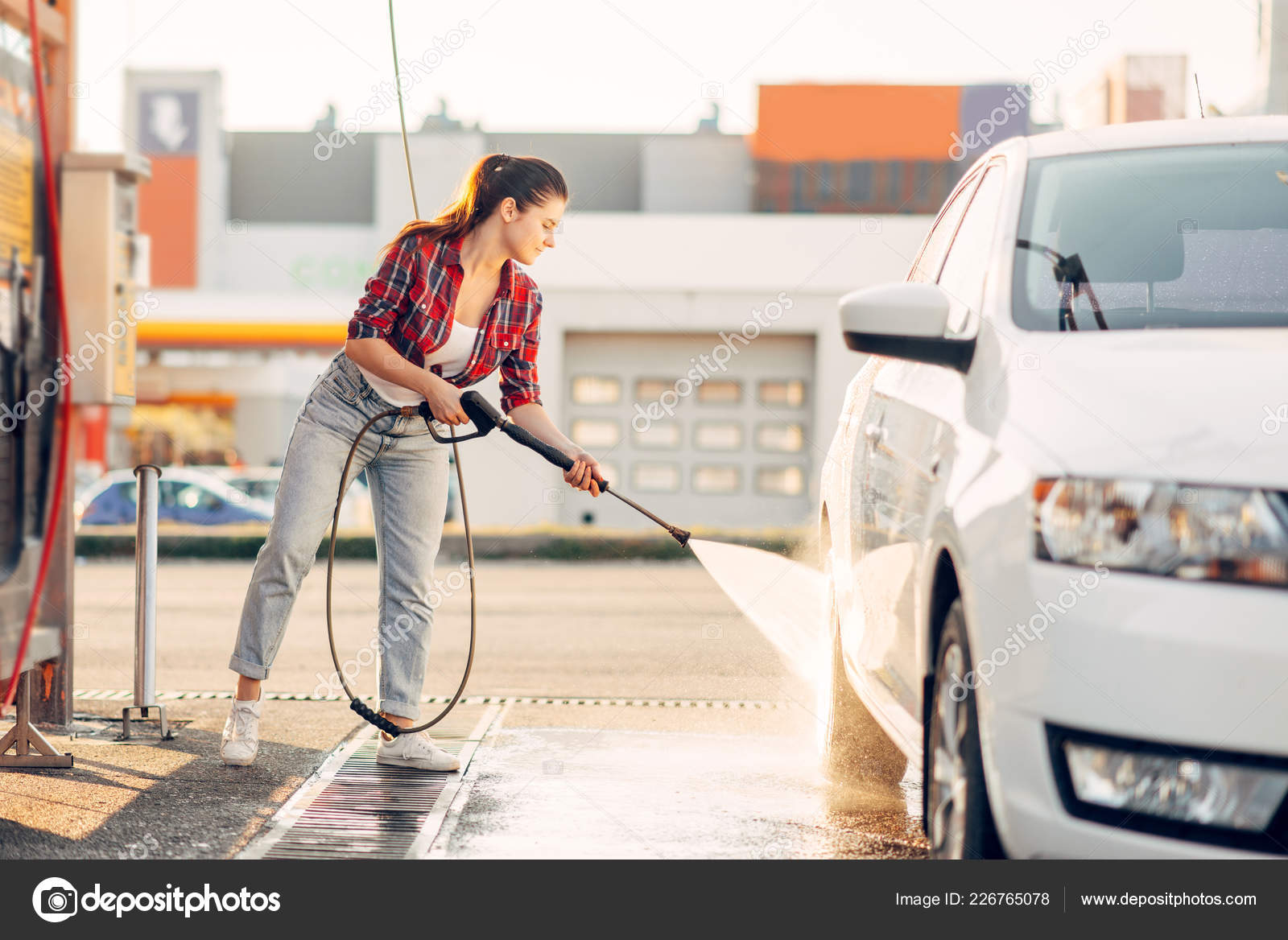 Frau reinigt die Windschutzscheibe des Autos mit Spray, Blick von