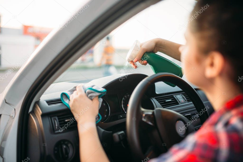 Female person polishes the dashboard of the car, polishing process on carwash. Lady on self-service automobile wash. Outdoor vehicle cleaning