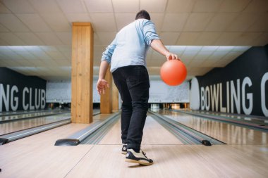 Erkek Melon ayakta lane ve pozlar elinde topuyla, arkadan görünüm. Bowling salonu oyuncu hazırlar vurulmuş grev atmak club, etkin boş