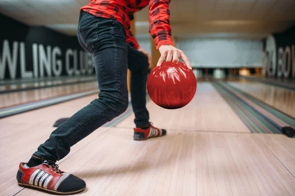 Male bowler makes throw, closeup view on hand with ball. Bowling alley player, throwing in action, classical tenpin game in club