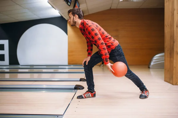 Male bowler makes throw, closeup view on hand with ball. Bowling alley player, throwing in action, classical tenpin game in club, active leisure