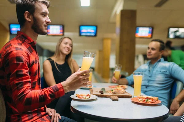 Friends drinks juice and eat pizza in bowling club, active leisure, healthy lifestyle, bowling game