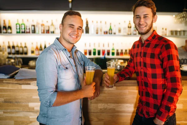 Two male bowlers drinks fresh juice at the bowling club bar counter. Players relax after competition. Active leisure, healthy lifestyle