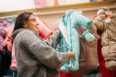 Gelecekte anne yeni doğan, bez bölümü deposunda. Bebekler için malların dükkanda hamile kadın