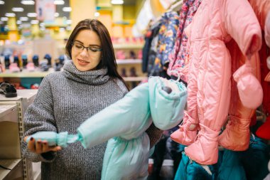 Gelecekte anne yeni doğan, bez bölümü deposunda. Bebekler için malların dükkanda hamile kadın