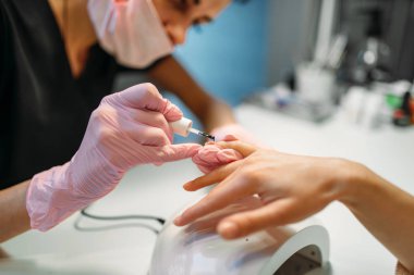Şevval özçelik güzellik pembe eldiven sopa içinde kadın müşteri, tırnak manikür güzellik salonunda. Manikürcü El Bakımı kozmetik prosedür yapıyor