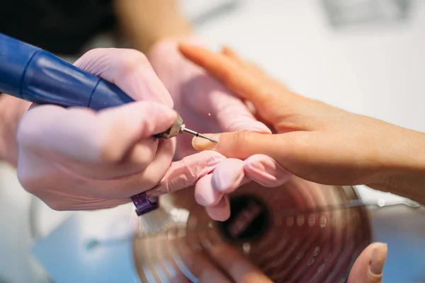 女性のクライアント 平面図 美容院でマニキュアの爪を研磨手袋で美容師 ネイリストの手のケア化粧品の手順を行う — ストック写真