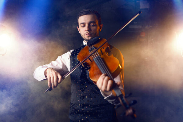 portrait of young male musician playing violin, fiddler with musical instrument