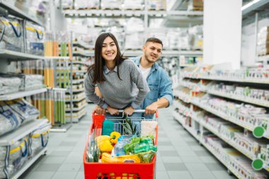 Çift arabası tam bir süpermarkette malların ile aile alışveriş. Müşteriler alıcılar pazarında eşya,