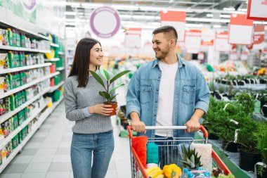 Çift arabası tam bir süpermarkette eve çiçek satın mal ile aile alışveriş. Müşteriler alıcılar pazarında eşya,