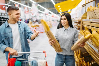 Birkaç taze somun seçerek bir süpermarkette arabası ile aile alışveriş. Müşteriler alıcılar pazarında eşya,