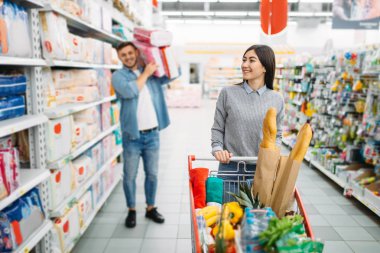 Bir sürü çocuk bezi bir süpermarkette satın sepeti ile mutlu çift aile alışveriş. Müşteriler Dükkanı, piyasada alıcı, çocuklar için malların bölümü