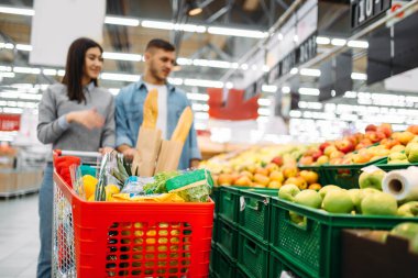 Çift arabası süpermarkette, meyve bölümü, ile aile alışveriş. Müşteriler alıcılar pazarında eşya,