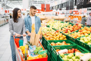 Çift arabası süpermarkette, meyve bölümü, ile aile alışveriş. Müşteriler alıcılar pazarında eşya,