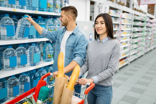 Young Couple Cart Takes Canister Water Shelf Supermarket Family Shopping — Stock Photo, Image