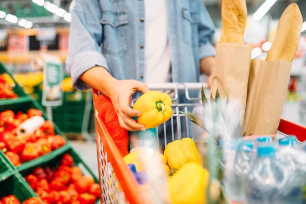 Erkek kişi ürünlerle bir süpermarkette arabası sarı biber koyar aile alışveriş. Eşya, piyasada alıcı müşteri
