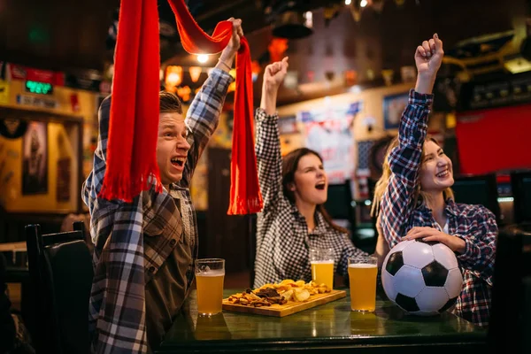 Football fans with scarf watching match and raise their hands up in sports bar. Tv broadcasting, young friends in pub, favorite team wins