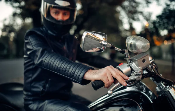 Biker in helmet poses on a motorcycle, classical chopper. Vintage bike, rider and his two-wheeled friend, freedom lifestyle, biking