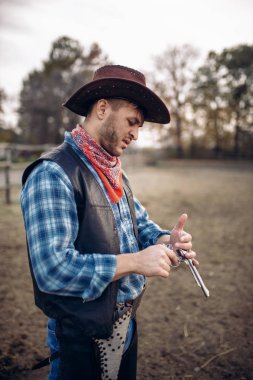 Kovboy tabancasını çiftlikte, Batı silahlı çatışma önce denetler. Çiftlikte, vahşi batı macera silahla Vintage erkek kişi