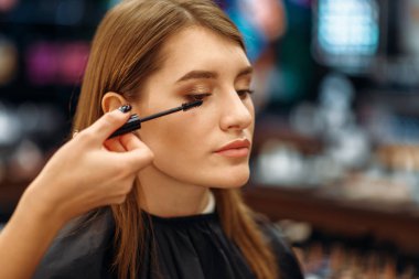 Makyaj salonu makyajcısı ve erkek müşteri. Kadın müşteri ve güzellik salonları, makyaj yordamı, profesyonel visagiste ve Bayan Güzellik uzmanı