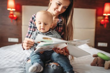 Genç Anne ve küçük erkek çocuk okuma bir kitap, çocuklara eğitim. Anne ve oğlu birlikte ev, beraberlik mutlu