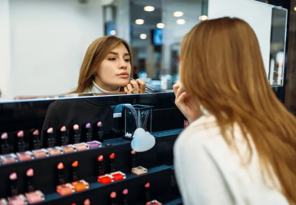 Female client testing lip liner in the make-up shop. Cosmetics choosing in beauty store, makeup salon