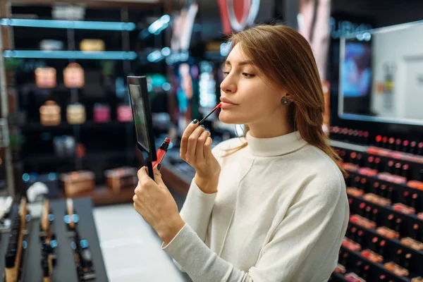 Female customer testing lip liner in the makeup shop. Cosmetics choosing in beauty store, make-up