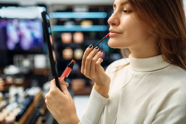 Female customer testing lip liner in the makeup shop. Cosmetics choosing in beauty store, make-up