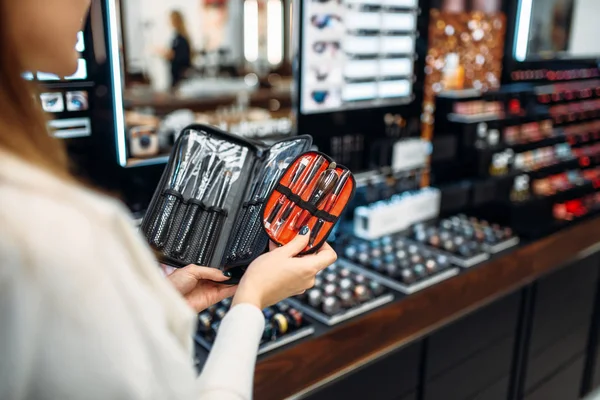 Female customer choosing cosmetics tools in the makeup shop. Nail varnish choosing in beauty store, make-up salon