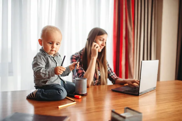 Mother works at home little kid helps her. Mom and son happy together at home, togetherness