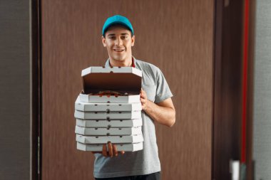 Teslimatçı taze pizza servisi teslim kutusunda gösterir. Pizzacı gelen kurye karton paketler kapalı tutan