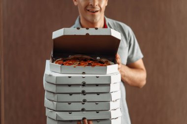 Teslimatçı taze pizza servisi teslim kutusunda gösterir. Pizzacı gelen kurye karton paketler kapalı tutan