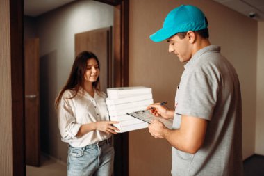 Kadın müşteri siparişi imzalar, pizza servis elemanı karton kutularda, hızlı hizmet teslim almıştır. Pizzacı ve kapıdaki kadın kurye