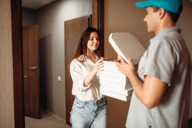 Kadın müşteri ve teslimat çocuk pizza, hizmet teslim hızlı denetler. Pizzacı ve kapıdaki kadın kurye