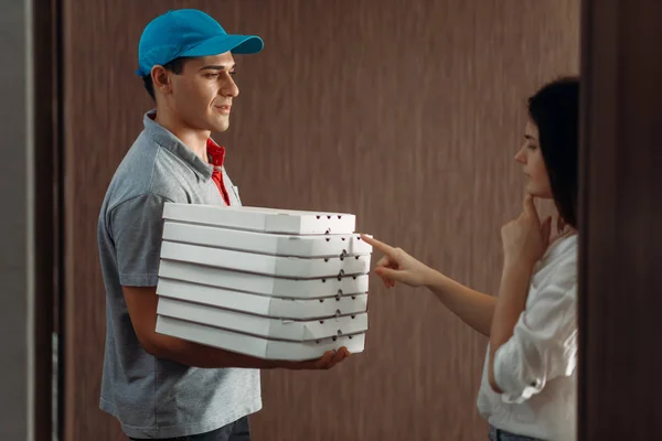 Female customer on the doorstep and pizza delivery boy, delivering service. Deliver from pizzeria and woman indoor