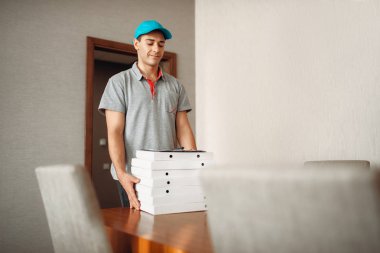 Pizza servis elemanı hizmet teslim emir masaya bırakır. Pizzacı gelen kurye karton paketler kapalı tutan