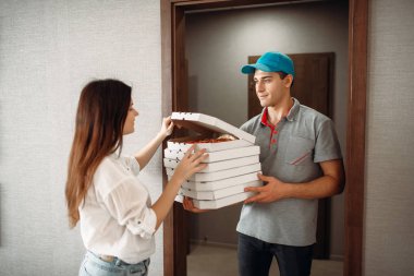 Teslimatçı taze ve sıcak pizza servisi teslim kadın müşteri için kapıda gösterir. Pizzacı ve kadın girişine yakın eve teslim