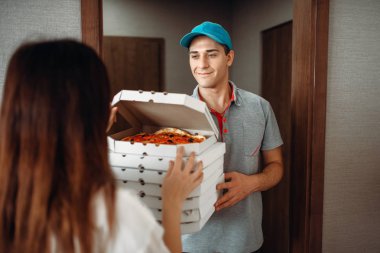 Teslimatçı taze ve sıcak pizza servisi teslim kadın müşteri için kapıda gösterir. Pizzacı ve kadın girişine yakın eve teslim