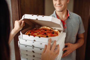 Teslimatçı taze ve sıcak pizza servisi teslim kadın müşteri için kapıda gösterir. Pizzeria ve kadın girişine yakın daire, pizzaman ve alıcı için teslim