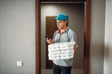 Pizza servis elemanı müşteri hizmeti sunan, t-shirt ve şapka çağrıları. Pizzacı gelen kurye karton paketler ve telefon kapalı tutar