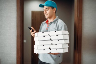 Pizza servis elemanı müşteri hizmeti sunan, t-shirt ve şapka çağrıları. Pizzacı gelen kurye karton paketler ve telefon tutar